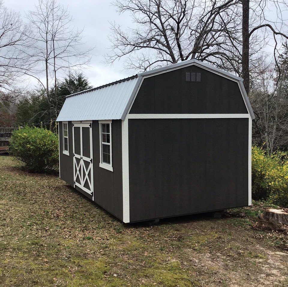 A black shed with white trim by Liberty Sheds.