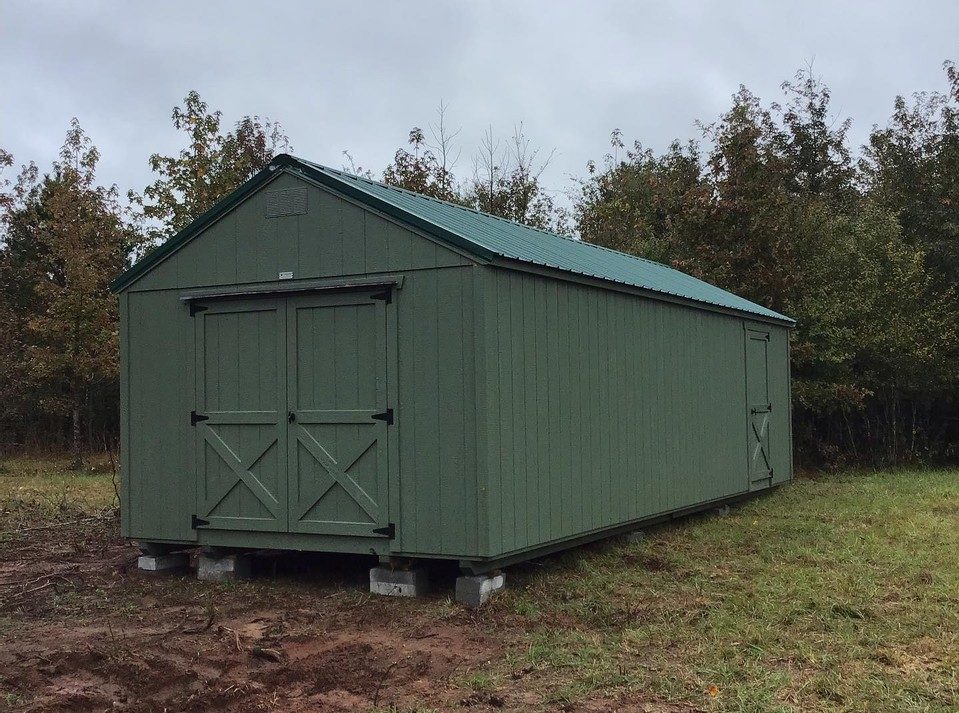 A green shed with green trim by Liberty Sheds.